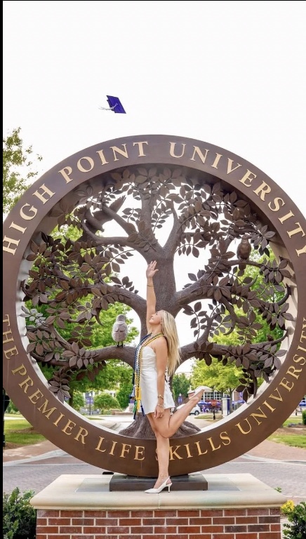 Kielan Oday at the High Point University tree-of-life sculpture on graduation day, May 2025